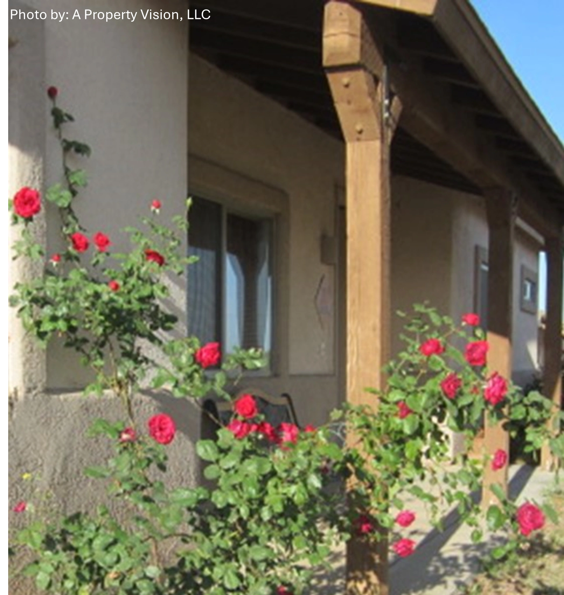 Property entrance with red roses and wood beam porch